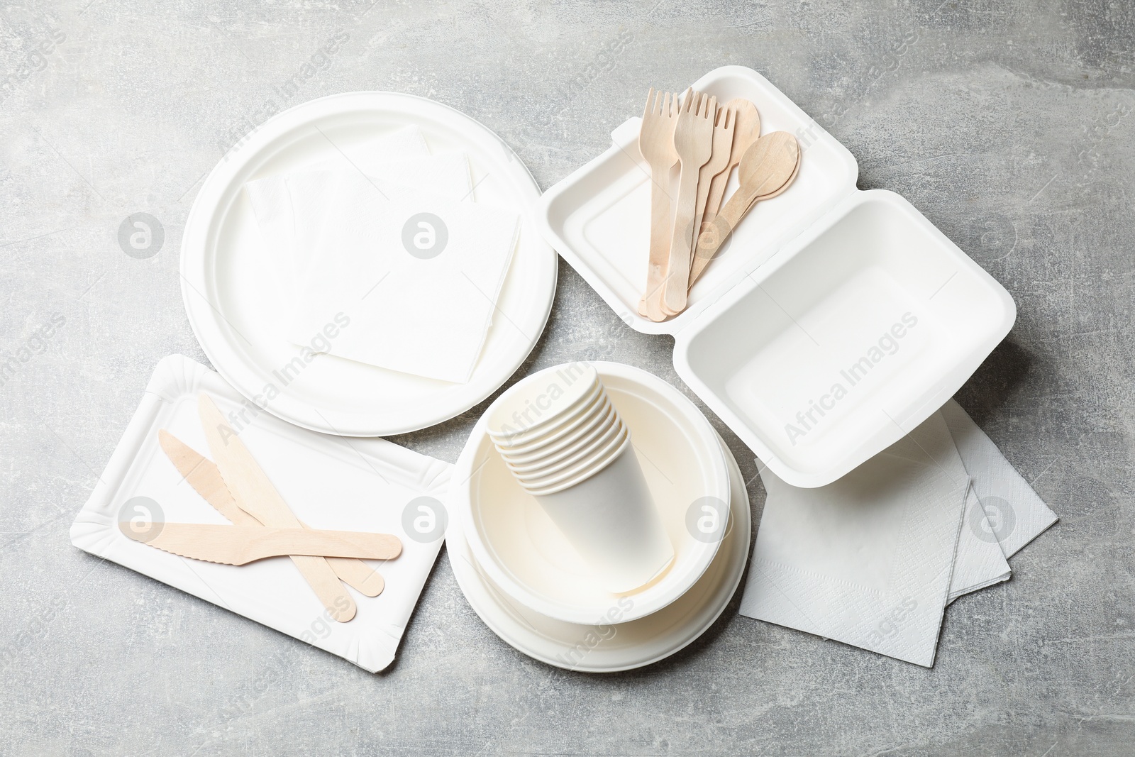 Photo of Set of disposable tableware and napkins on grey table, flat lay