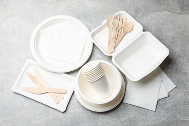 Photo of Set of disposable tableware and napkins on grey table, flat lay