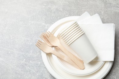Photo of Set of disposable tableware and napkins on grey table, top view. Space for text