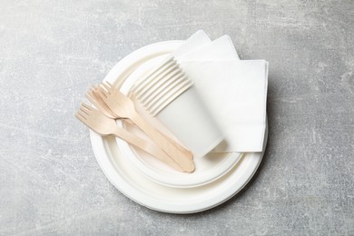 Photo of Set of disposable tableware and napkins on grey table, top view