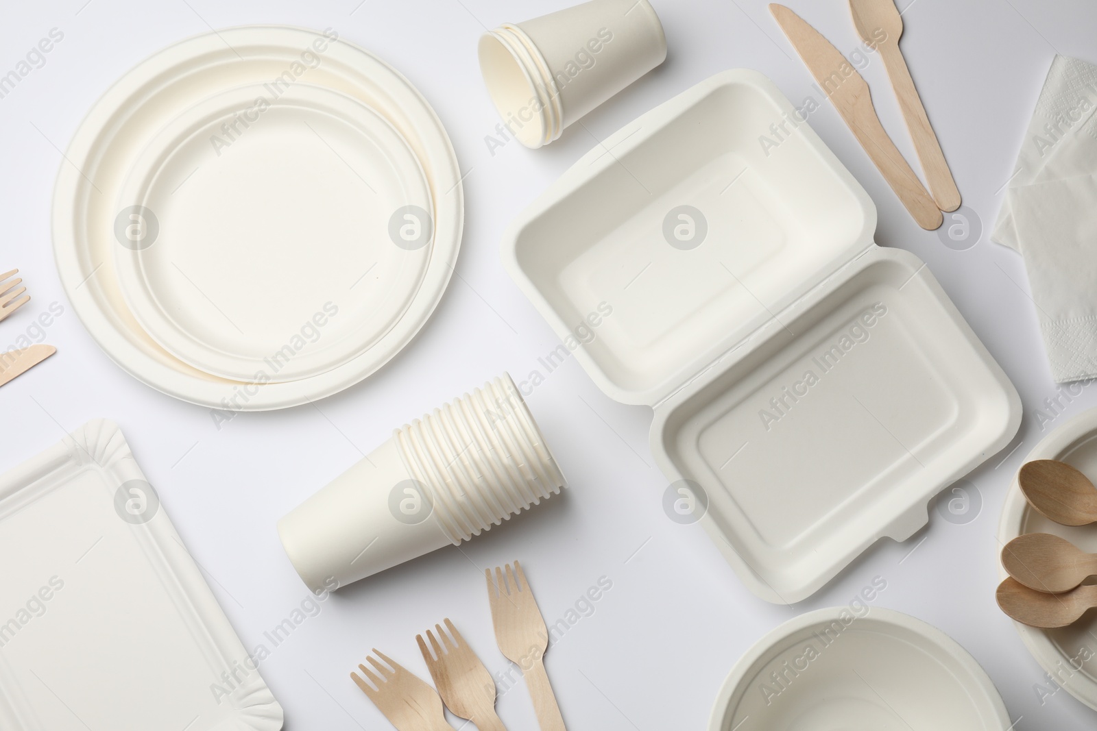 Photo of Set of disposable tableware and napkins on white background, flat lay