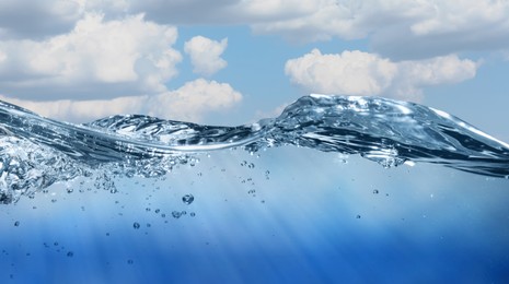 Image of Sea water surface and underwater view. Sky with clouds above