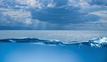 Image of Sea water surface and underwater view. Sky with clouds above