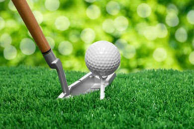 Image of Golf ball, tee, club and green grass against blurred background