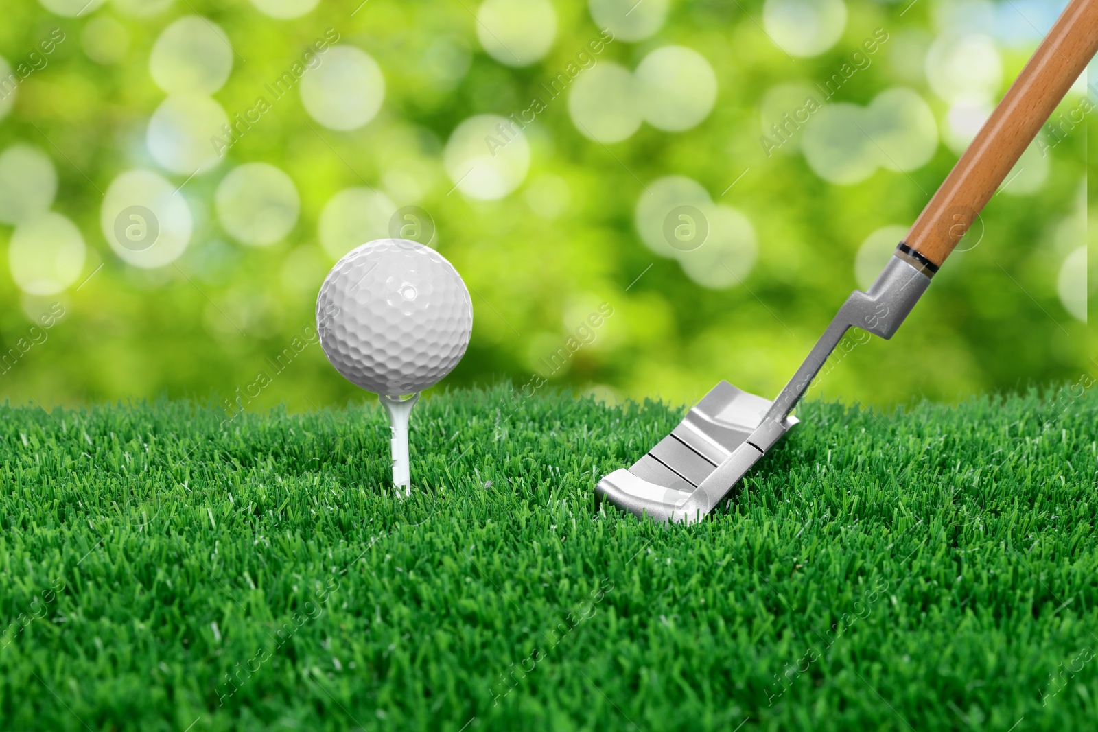 Image of Golf ball, tee, club and green grass against blurred background