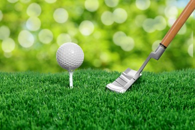 Image of Golf ball, tee, club and green grass against blurred background