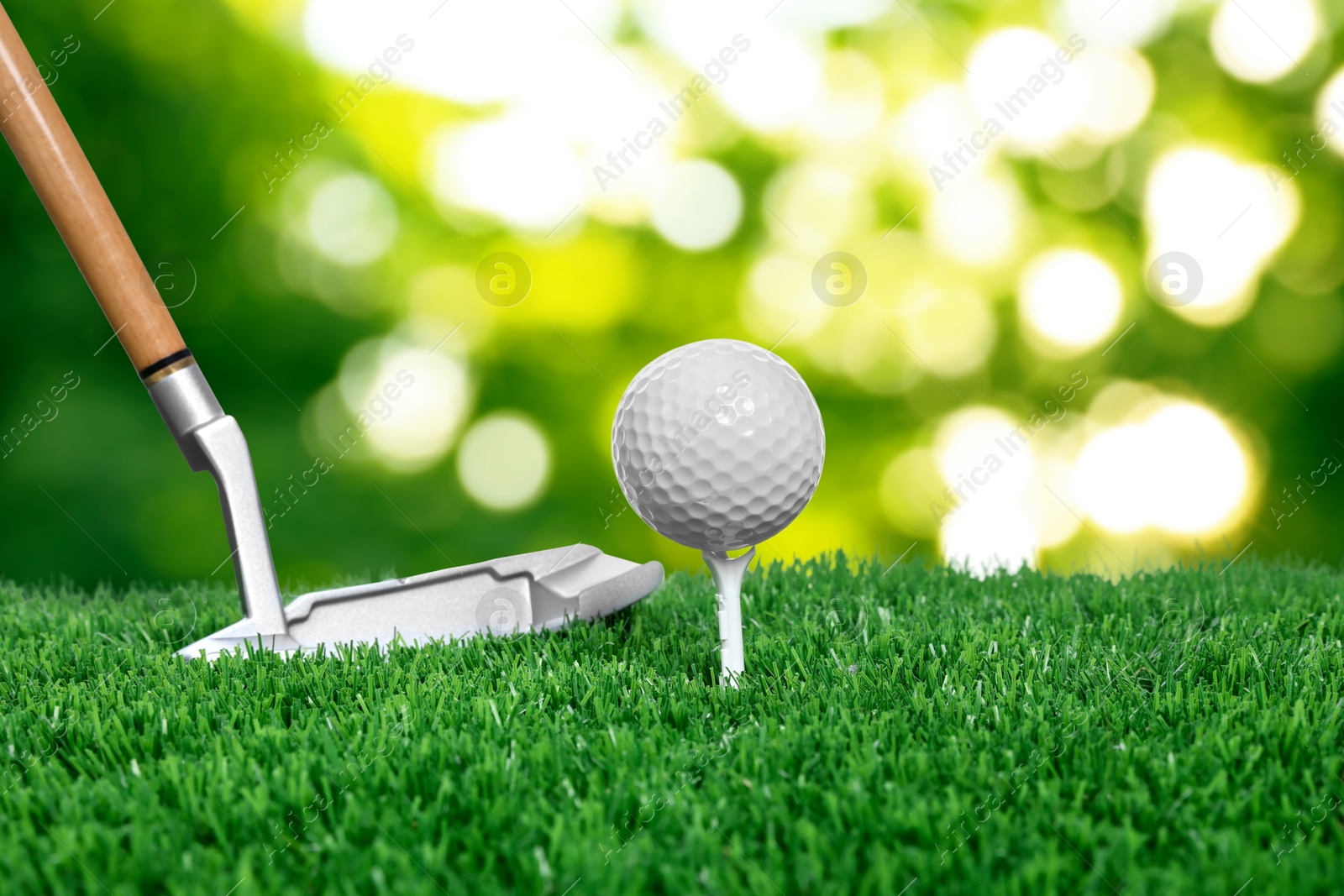 Image of Golf ball, tee, club and green grass against blurred background