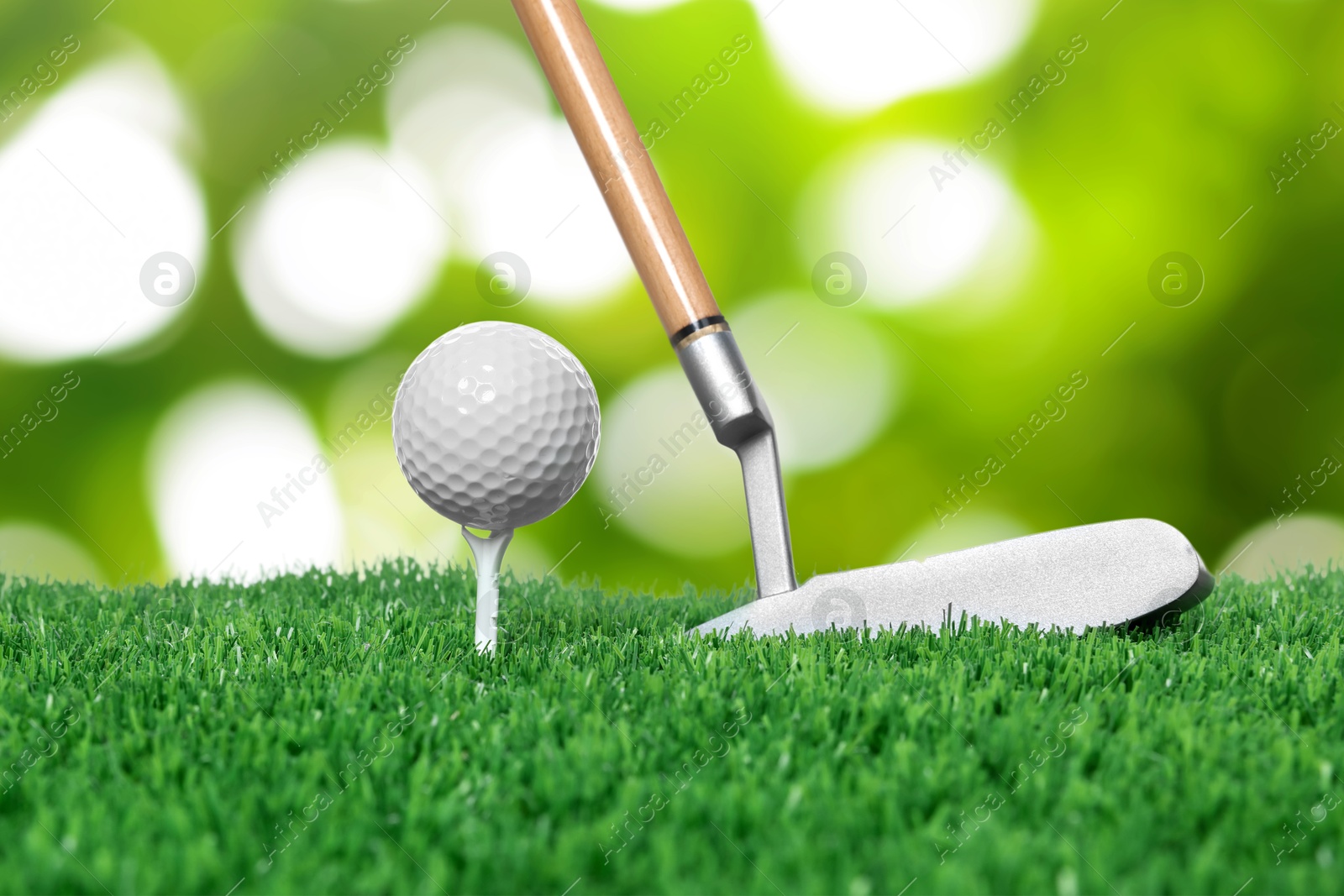 Image of Golf ball, tee, club and green grass against blurred background