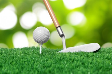 Image of Golf ball, tee, club and green grass against blurred background