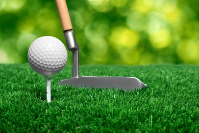 Image of Golf ball, tee, club and green grass against blurred background