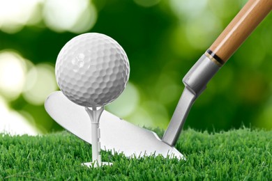 Image of Golf ball, tee, club and green grass against blurred background