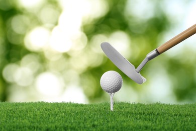 Image of Golf ball, tee, club and green grass against blurred background