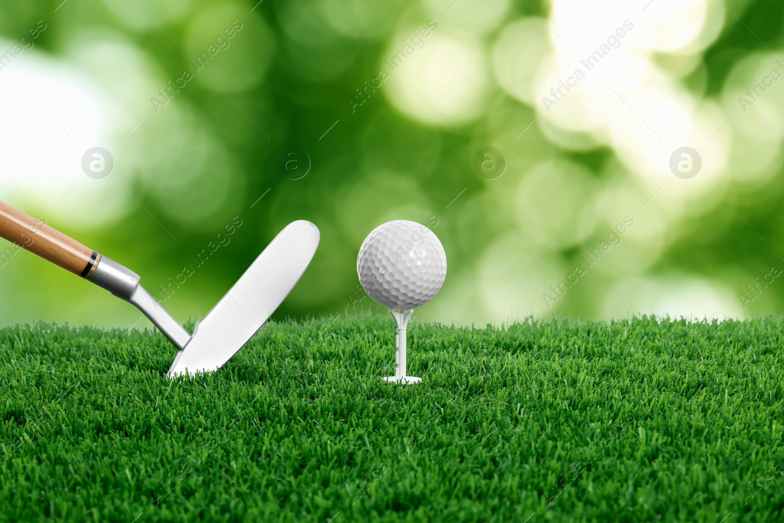 Image of Golf ball, tee, club and green grass against blurred background