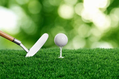 Image of Golf ball, tee, club and green grass against blurred background