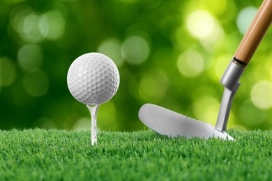 Image of Golf ball, tee, club and green grass against blurred background