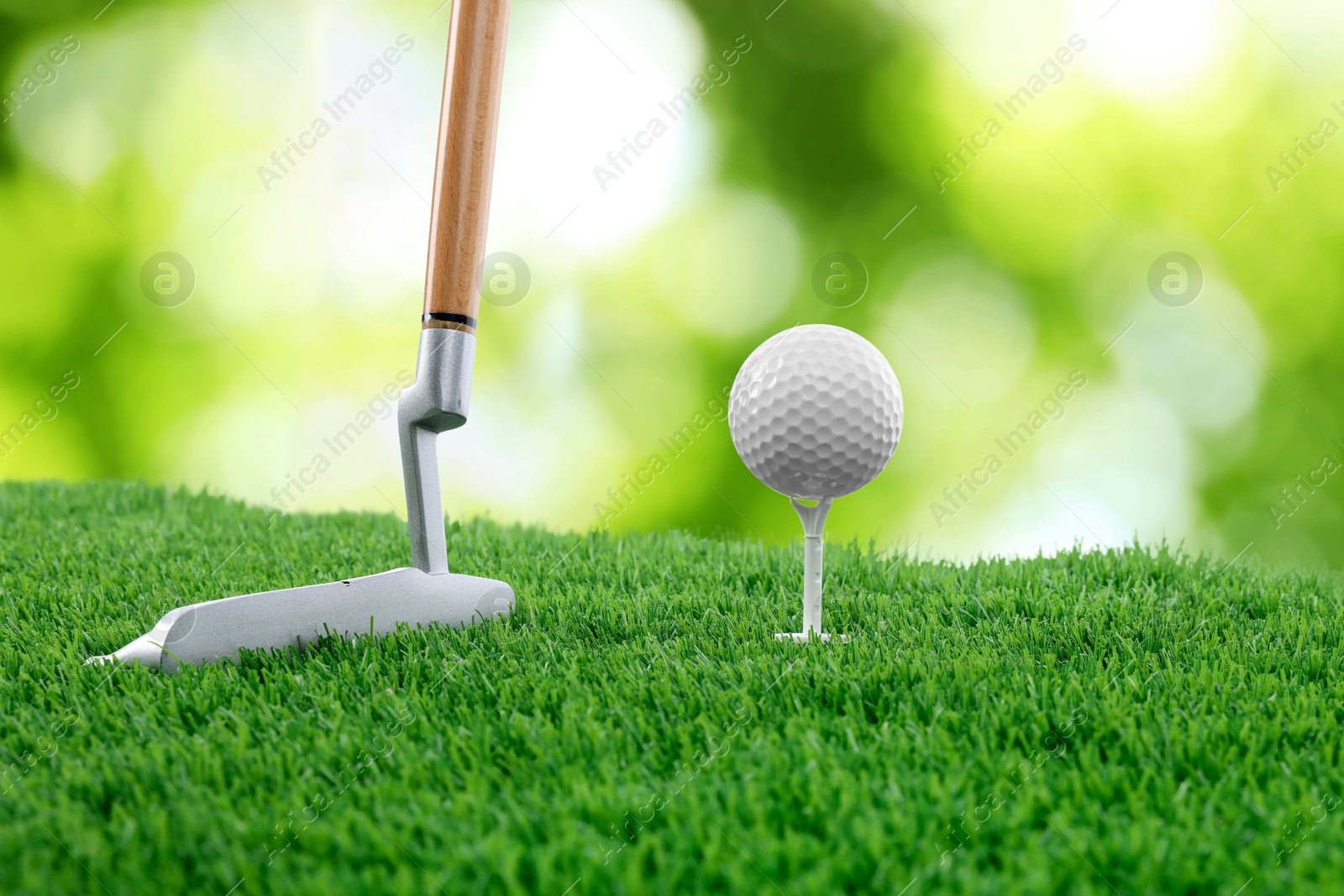 Image of Golf ball, tee, club and green grass against blurred background