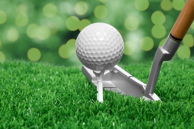 Image of Golf ball, tee, club and green grass against blurred background