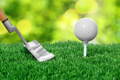 Image of Golf ball, tee, club and green grass against blurred background
