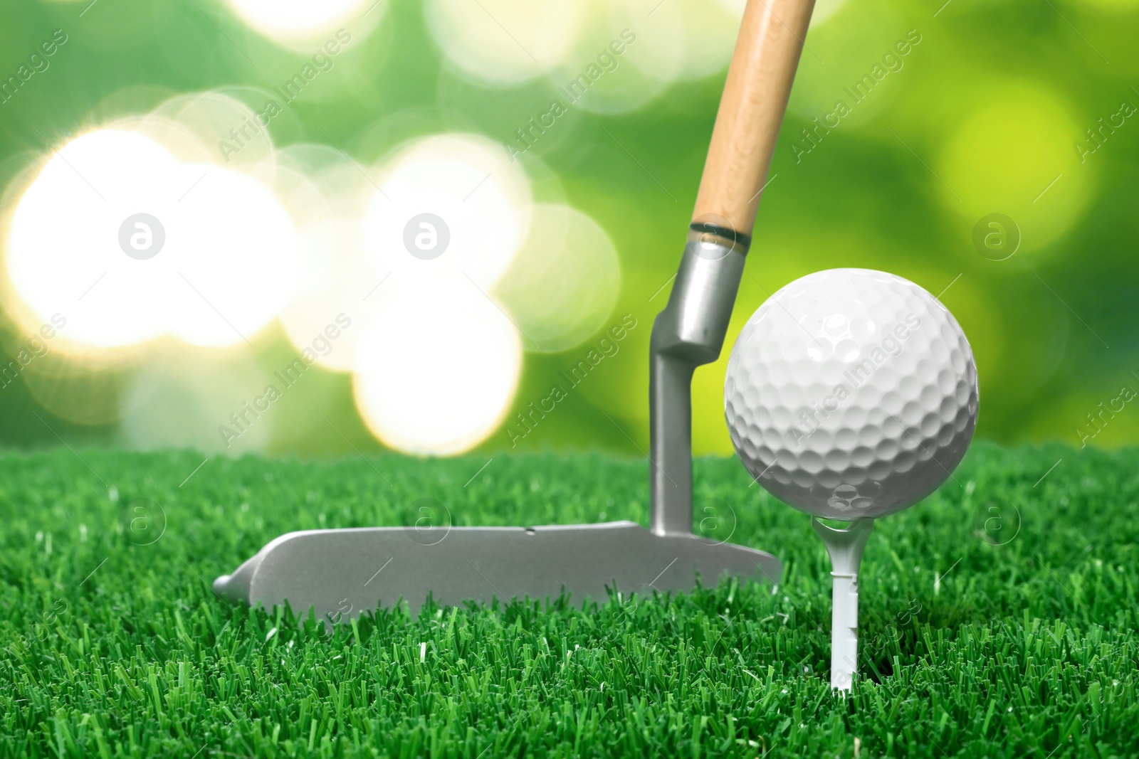 Image of Golf ball, tee, club and green grass against blurred background
