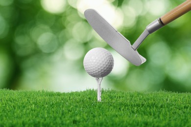 Image of Golf ball, tee, club and green grass against blurred background