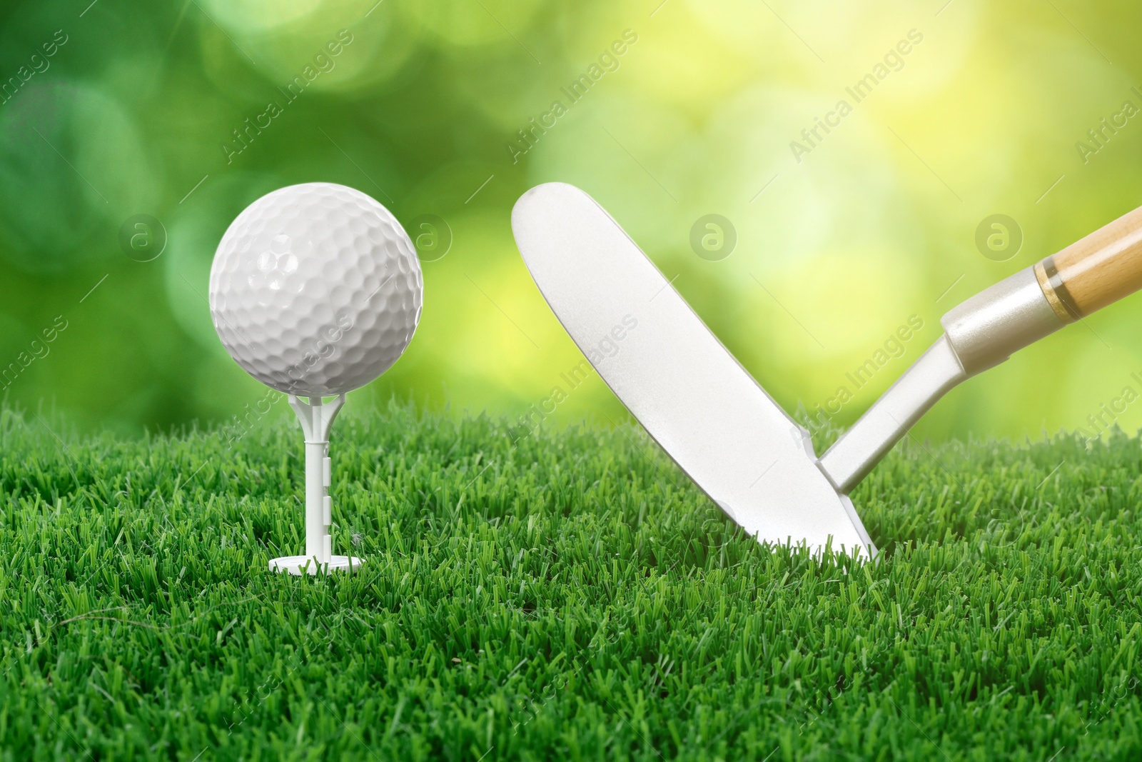 Image of Golf ball, tee, club and green grass against blurred background