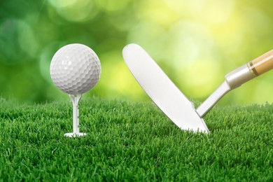 Image of Golf ball, tee, club and green grass against blurred background