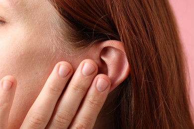 Photo of Sound. Woman touching her ear on pink background, closeup