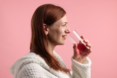 Photo of Woman rinsing mouth with mouthwash on pink background