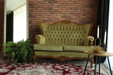 Photo of Green retro sofa, mirror, decor and houseplant in room. Interior design
