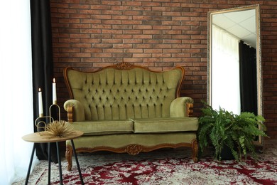 Photo of Green retro sofa, mirror, decor and houseplant in room. Interior design