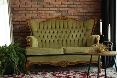 Photo of Green retro sofa, decor and houseplant in room. Interior design