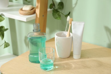 Photo of Mouthwash, toothbrushes and toothpaste on shelf in bathroom