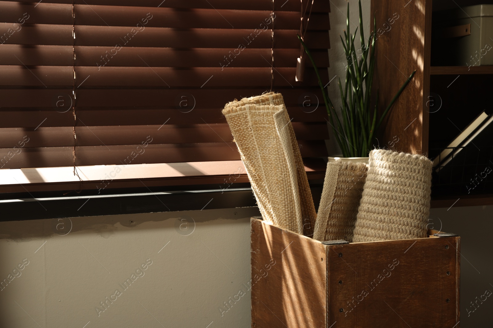 Photo of Different rugs in wooden box near window indoors. Used stuff