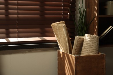 Photo of Different rugs in wooden box near window indoors. Used stuff