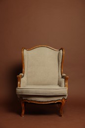 Photo of Stylish armchair on brown background. Used stuff