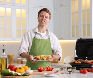 Photo of Man with freshly grilled vegetables in kitchen