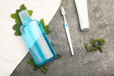 Photo of Mouthwash, other oral hygiene products and mint on grey table, flat lay