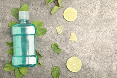 Photo of Mouthwash, other oral hygiene products, mint and lime slices on grey table, flat lay