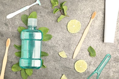 Photo of Mouthwash, other oral hygiene products, mint and lime slices on grey table, flat lay