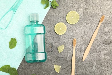 Photo of Mouthwash, other oral hygiene products, mint and lime slices on grey table, flat lay