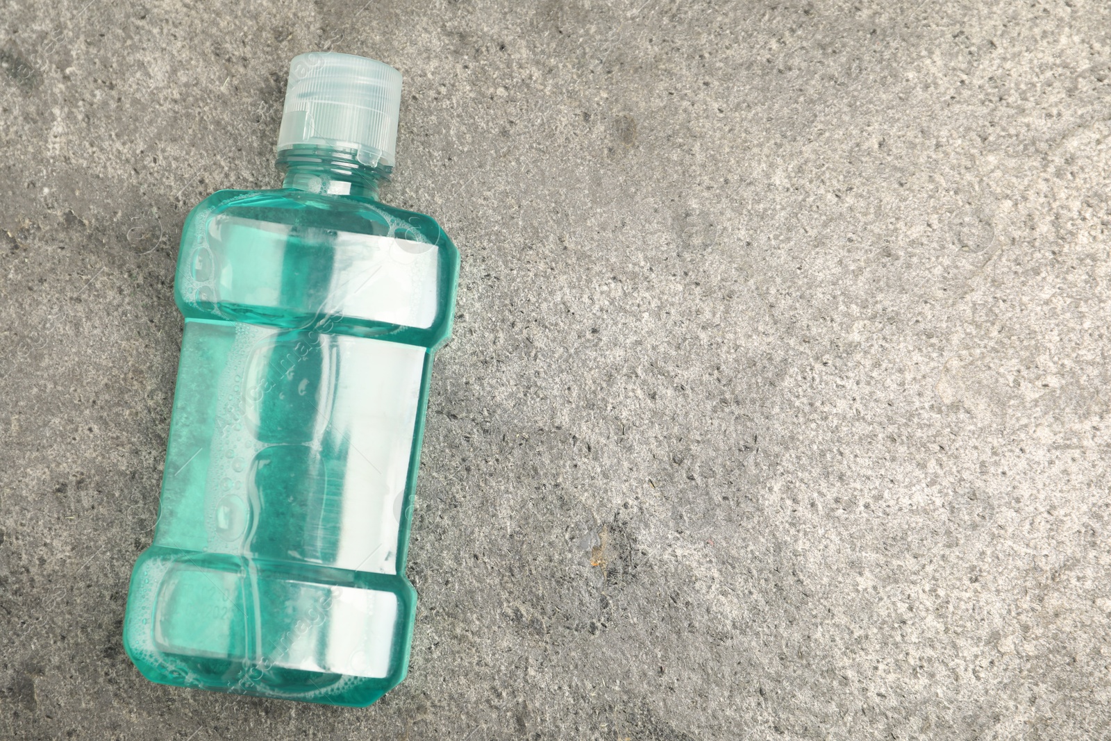 Photo of Bottle of mouthwash on grey table, top view. Space for text