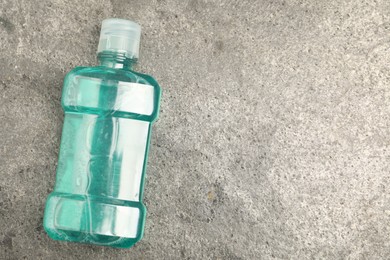Photo of Bottle of mouthwash on grey table, top view. Space for text
