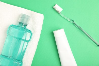 Photo of Mouthwash and other oral hygiene products on green background, flat lay