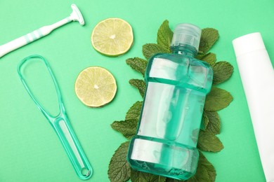 Photo of Mouthwash, other oral hygiene products, mint and lime slices on green background, above view