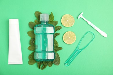 Photo of Mouthwash, other oral hygiene products, mint and lime slices on green background, flat lay