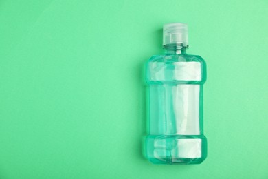 Photo of Bottle of mouthwash on green background, top view. Space for text