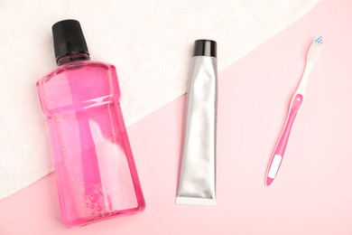 Photo of Mouthwash, toothbrush, toothpaste and towel on pink background, flat lay