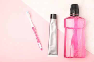Photo of Mouthwash, toothbrush, toothpaste and towel on pink background, flat lay
