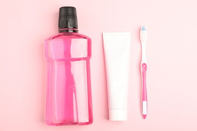 Photo of Mouthwash, toothbrush and toothpaste on pink background, flat lay