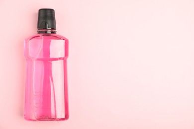 Photo of Bottle of mouthwash on pink background, top view. Space for text